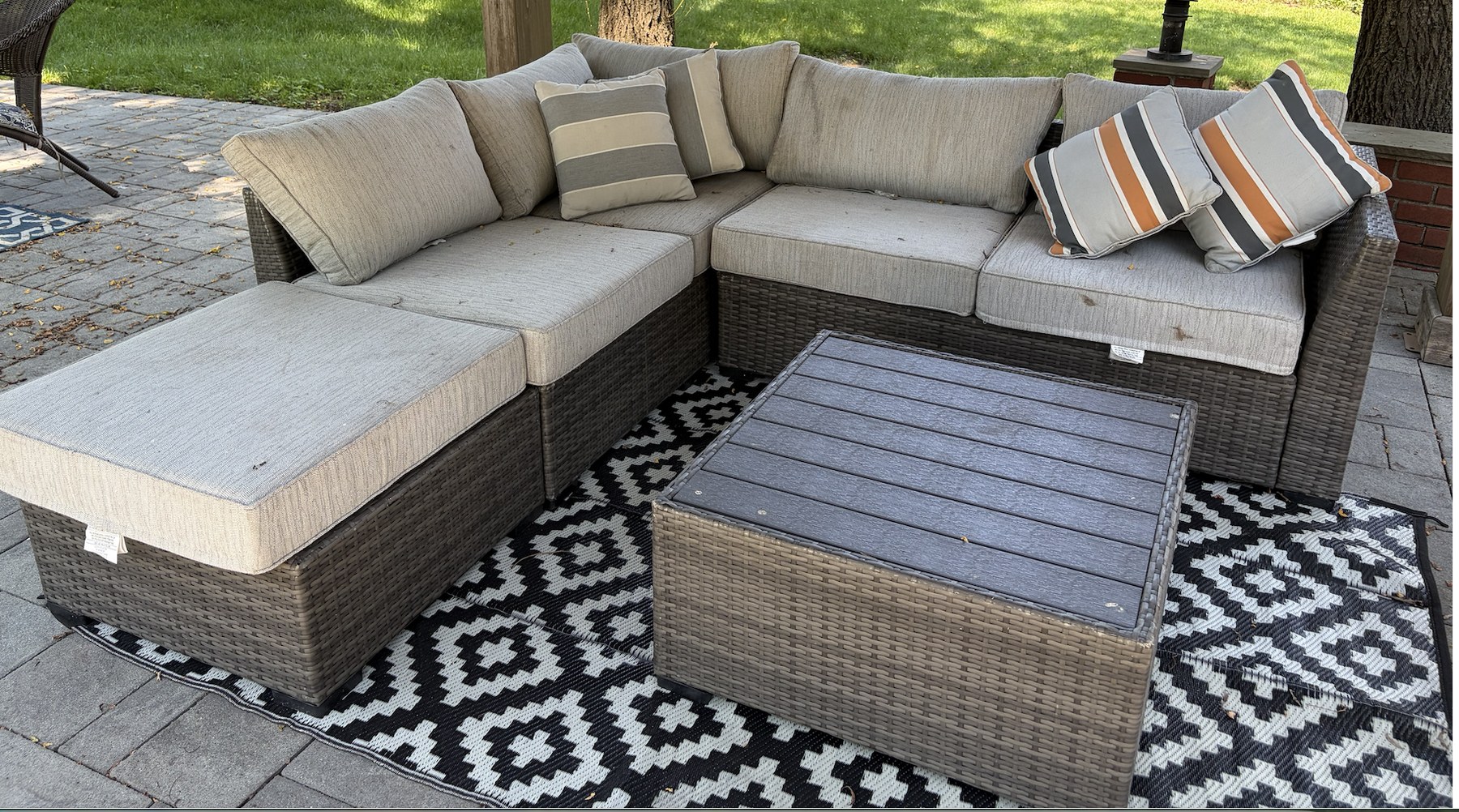 Grey-brown wicker outdoor sectional in a garden setting